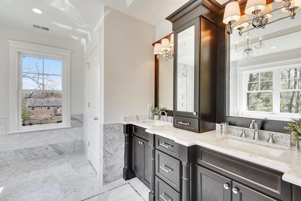 Inspiration for a mid-sized timeless master marble tile marble floor and white floor bathroom remodel in DC Metro with recessed-panel cabinets, brown cabinets, an undermount tub, gray walls, an undermount sink, marble countertops and white countertops