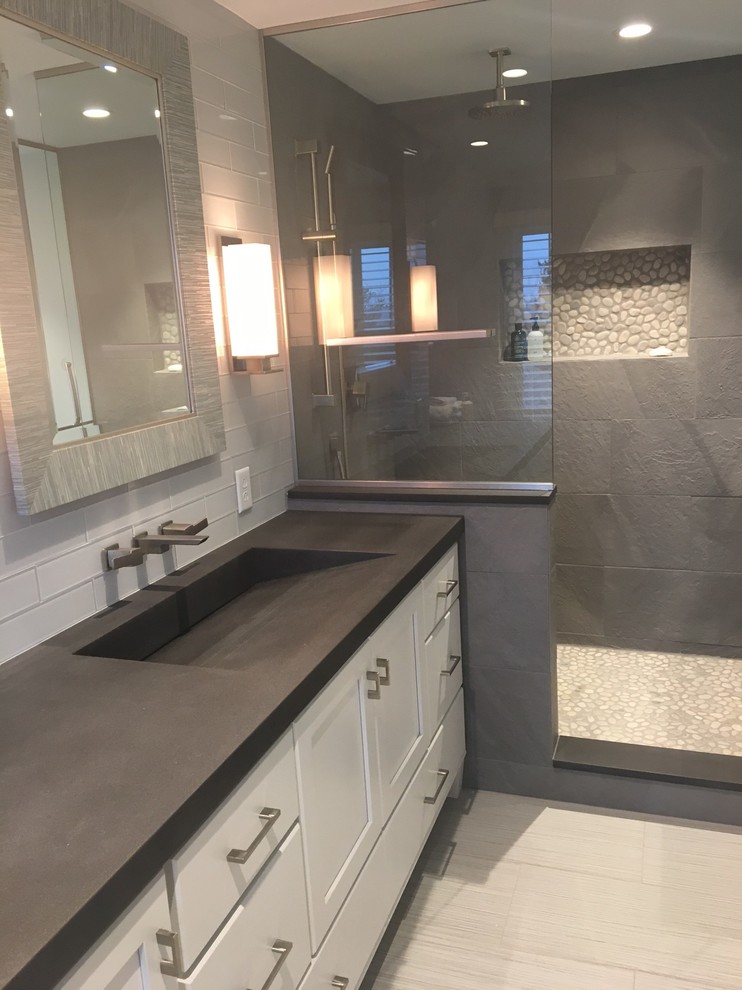 На фото: ванная комната в современном стиле с стеклянными фасадами, открытым душем, унитазом-моноблоком, серой плиткой, керамогранитной плиткой, полом из галечной плитки, монолитной раковиной и столешницей из бетона с