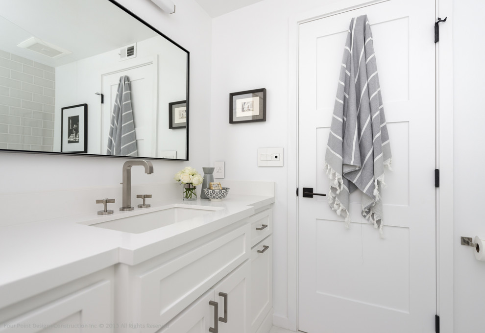 Cette photo montre une petite salle de bain principale tendance avec un placard à porte shaker, des portes de placard blanches, une baignoire encastrée, un combiné douche/baignoire, WC séparés, un carrelage gris, un carrelage métro, un mur blanc, un sol en marbre, un lavabo encastré et un plan de toilette en surface solide.