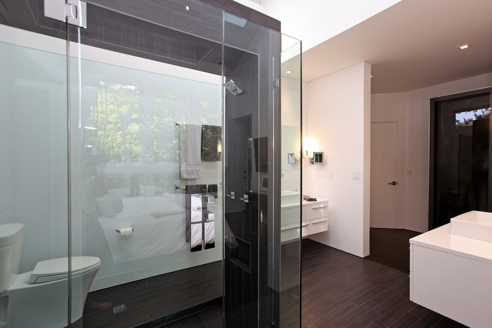 Modernes Badezimmer mit offener Dusche, Aufsatzwaschbecken, Toilette mit Aufsatzspülkasten, flächenbündigen Schrankfronten, weißen Schränken, Laminat-Waschtisch, schwarzen Fliesen, weißer Wandfarbe und dunklem Holzboden in New York