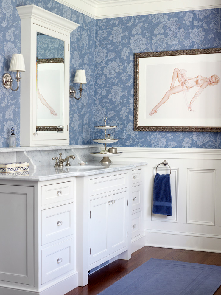 Réalisation d'une salle de bain tradition avec un lavabo encastré, des portes de placard blanches, un plan de toilette en marbre, un mur bleu et un placard à porte affleurante.