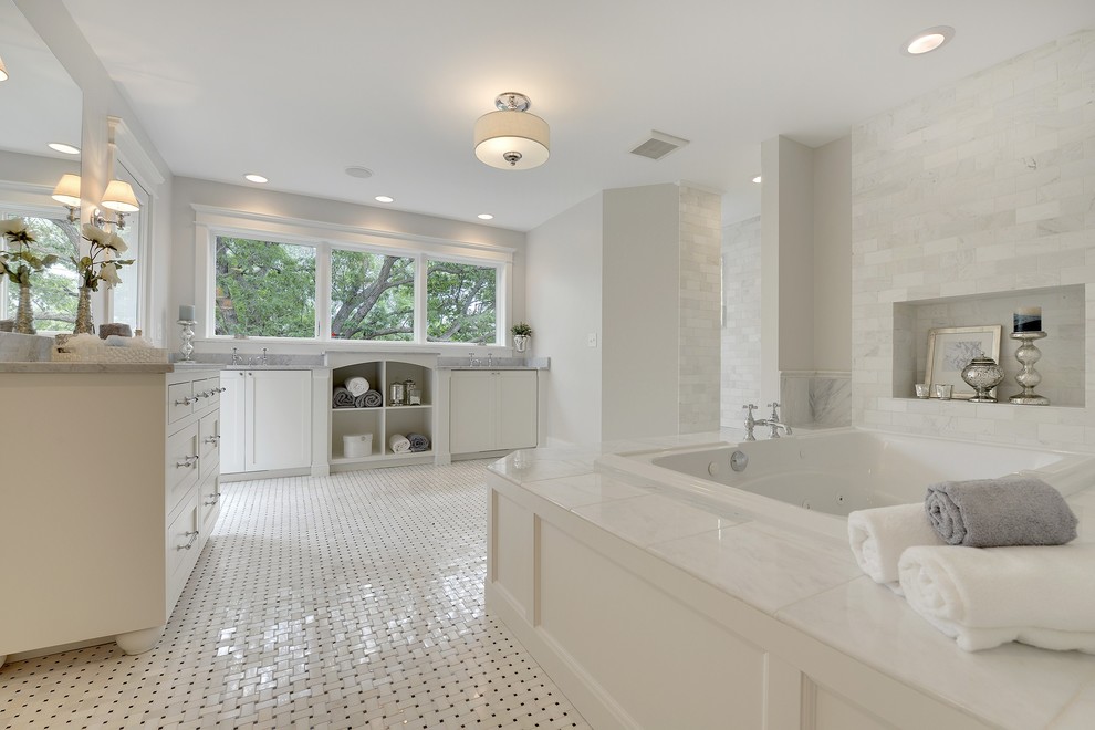 Klassisk inredning av ett en-suite badrum, med ett platsbyggt badkar, luckor med infälld panel, vita skåp, vit kakel, ett undermonterad handfat, marmorbänkskiva, en toalettstol med separat cisternkåpa, tunnelbanekakel, grå väggar och mosaikgolv