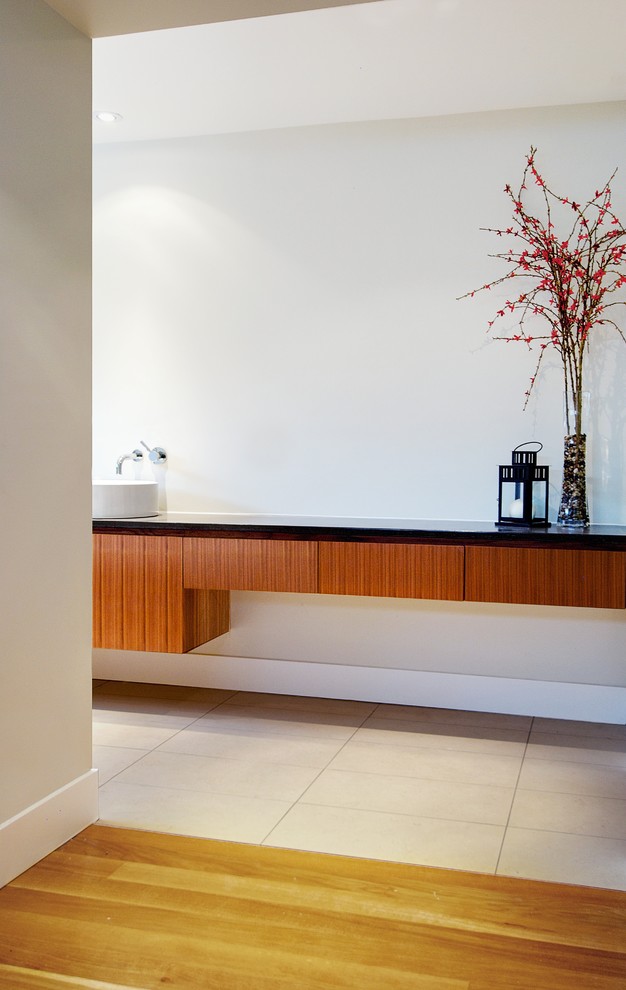 Стильный дизайн: главная ванная комната среднего размера в стиле модернизм с плоскими фасадами, коричневыми фасадами, белыми стенами, настольной раковиной, бежевым полом и черной столешницей - последний тренд