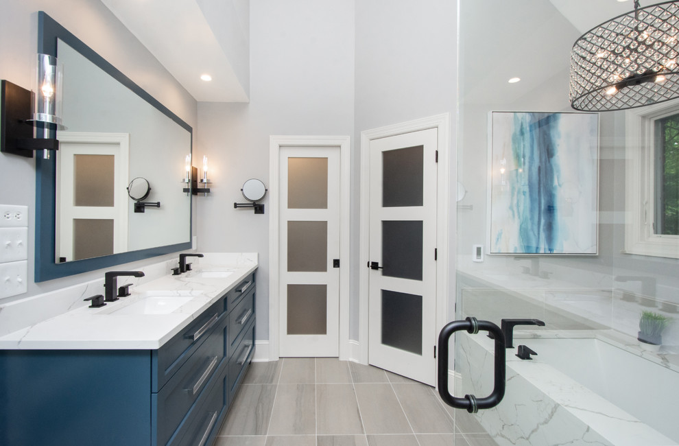 Свежая идея для дизайна: ванная комната в современном стиле с фасадами с утопленной филенкой, синими фасадами, полновстраиваемой ванной, душем в нише, раздельным унитазом, серой плиткой, серыми стенами, врезной раковиной, столешницей из искусственного кварца, серым полом, душем с распашными дверями и белой столешницей - отличное фото интерьера