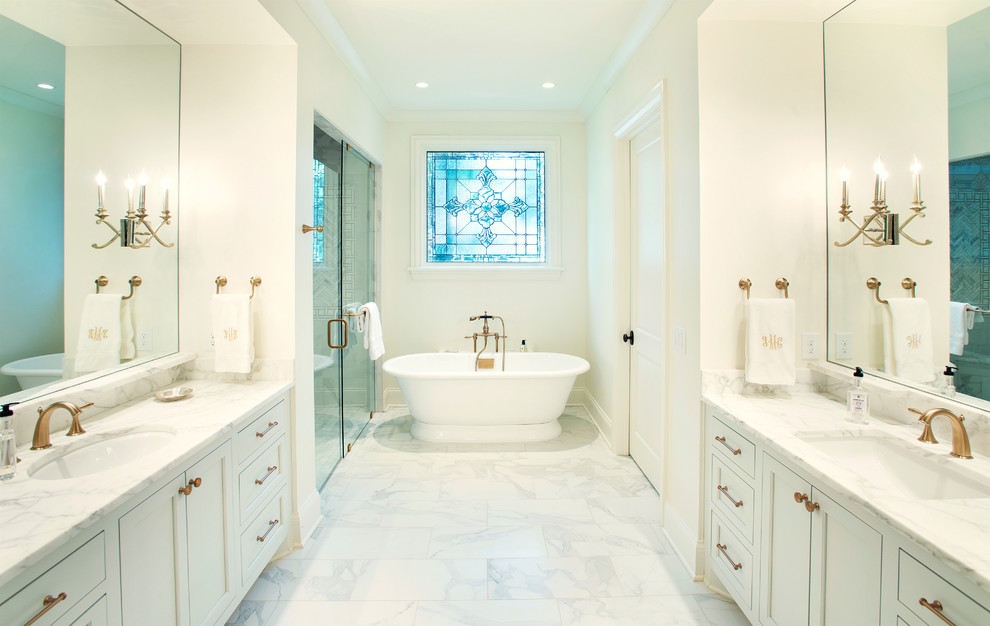 Exempel på ett klassiskt en-suite badrum, med luckor med profilerade fronter, vita skåp, ett fristående badkar, en kantlös dusch, en toalettstol med separat cisternkåpa, vit kakel, stenkakel, vita väggar, marmorgolv, ett undermonterad handfat och marmorbänkskiva