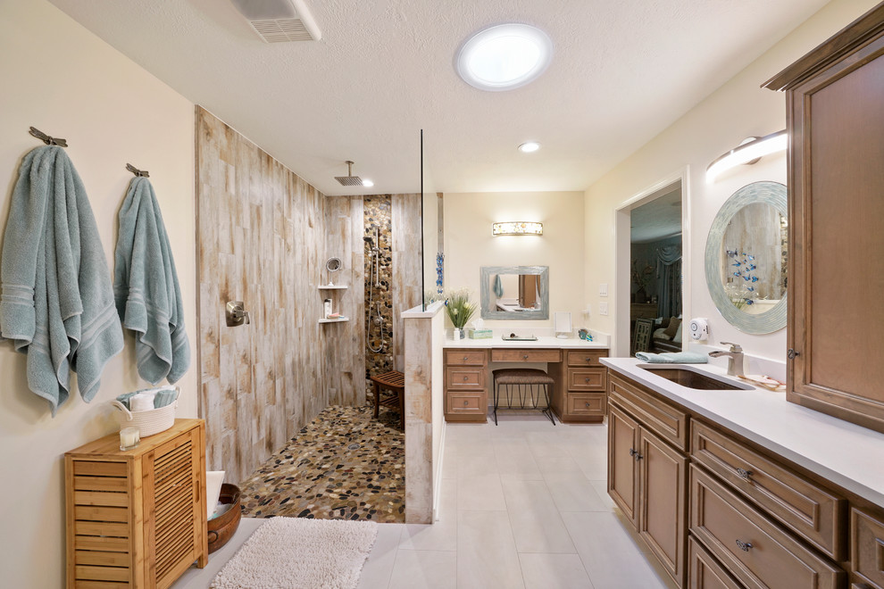 Klassisk inredning av ett mellanstort vit vitt en-suite badrum, med luckor med infälld panel, skåp i ljust trä, en kantlös dusch, en toalettstol med separat cisternkåpa, vit kakel, kakel i småsten, ett undermonterad handfat, bänkskiva i kvarts, med dusch som är öppen, beige väggar, klinkergolv i porslin och grått golv