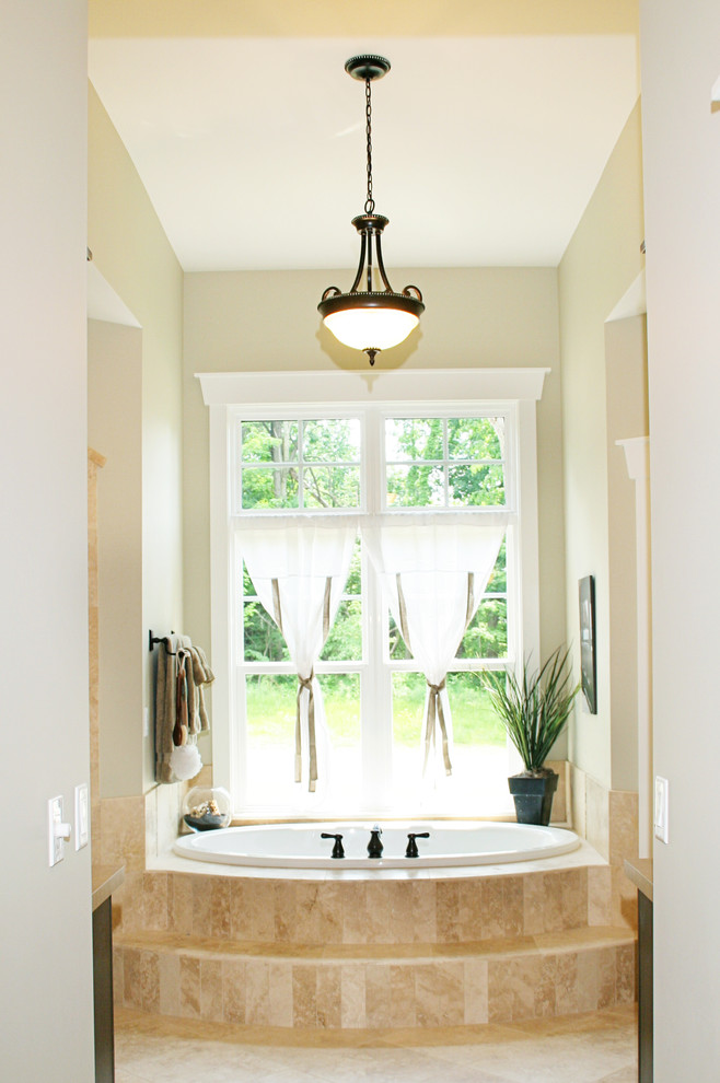 グランドラピッズにあるトラディショナルスタイルのおしゃれな浴室 (ドロップイン型浴槽、ベージュのタイル) の写真