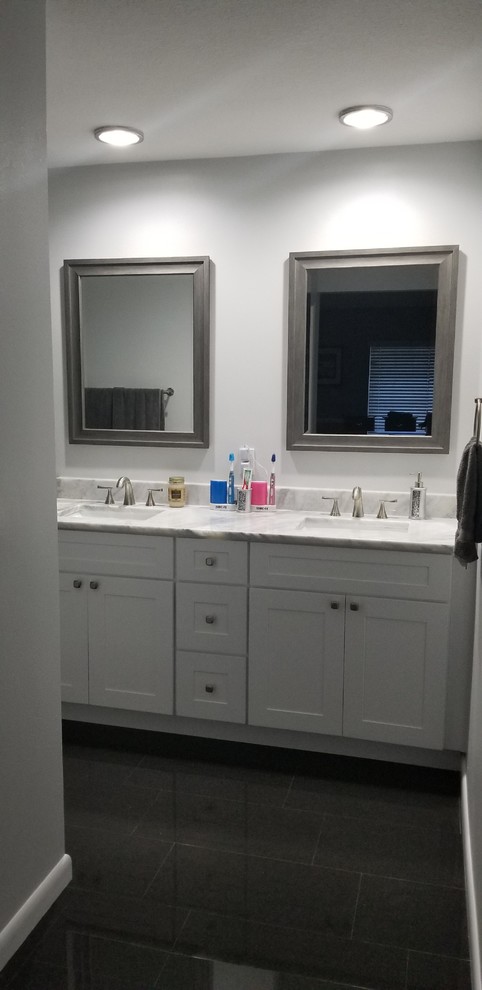 Inspiration for a medium sized modern ensuite bathroom in Tampa with shaker cabinets, white cabinets, grey tiles, stone slabs, grey walls, porcelain flooring, a submerged sink, granite worktops, black floors and grey worktops.