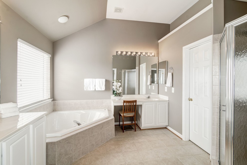Foto på ett stort vintage en-suite badrum, med luckor med upphöjd panel, vita skåp, ett hörnbadkar, beige kakel, porslinskakel, grå väggar, klinkergolv i porslin, granitbänkskiva och grått golv