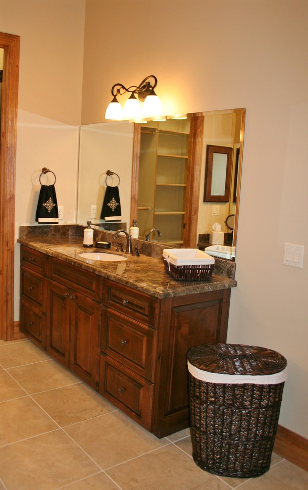 Inspiration pour une salle de bain principale chalet en bois brun avec un lavabo encastré, un placard avec porte à panneau surélevé, un plan de toilette en granite, un carrelage beige, des carreaux de porcelaine et un sol en carrelage de porcelaine.