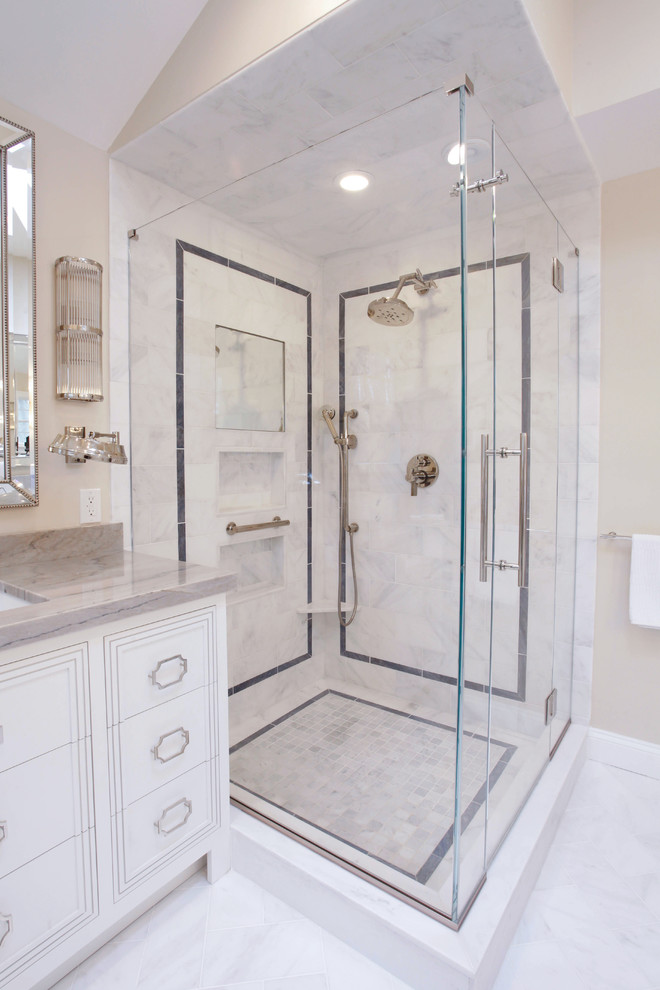 Mid-sized transitional master white tile and marble tile marble floor and white floor corner shower photo in New York with furniture-like cabinets, white cabinets, a one-piece toilet, gray walls, an undermount sink, quartzite countertops and a hinged shower door