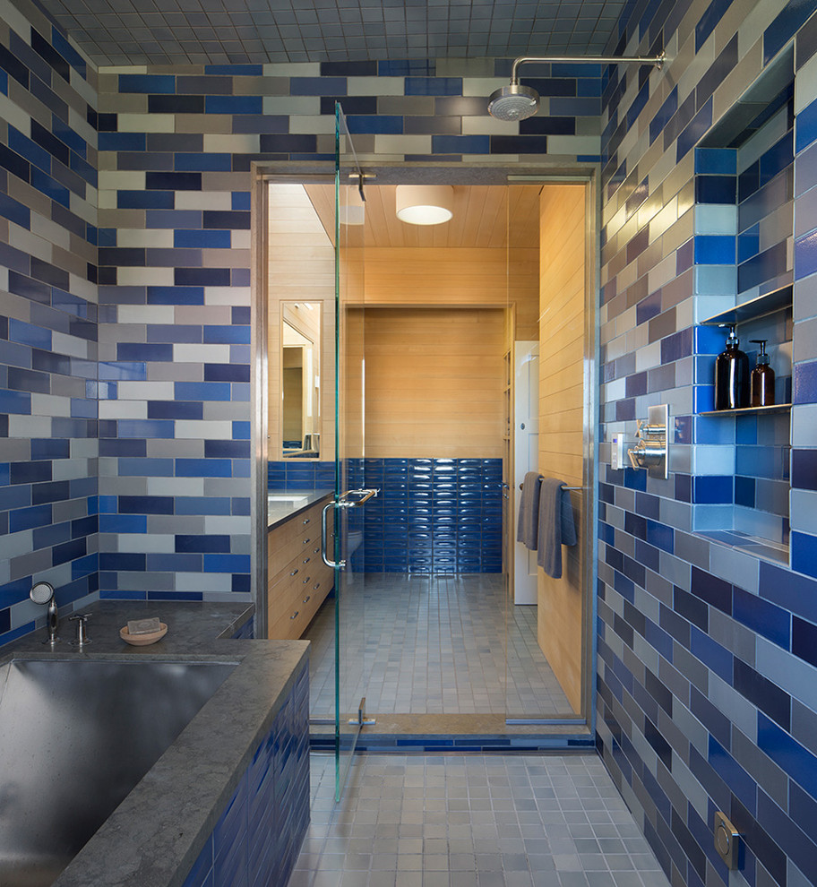 На фото: большая главная ванная комната в современном стиле с плоскими фасадами, светлыми деревянными фасадами, полновстраиваемой ванной, душевой комнатой, синей плиткой, керамической плиткой, коричневыми стенами, полом из керамической плитки, врезной раковиной, синим полом и душем с распашными дверями с
