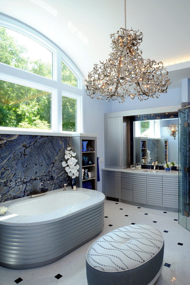 На фото: огромная главная ванная комната в современном стиле с фасадами островного типа, синими фасадами, полновстраиваемой ванной, душем без бортиков, раздельным унитазом, белой плиткой, плиткой из листового камня, белыми стенами, полом из керамогранита, врезной раковиной и мраморной столешницей