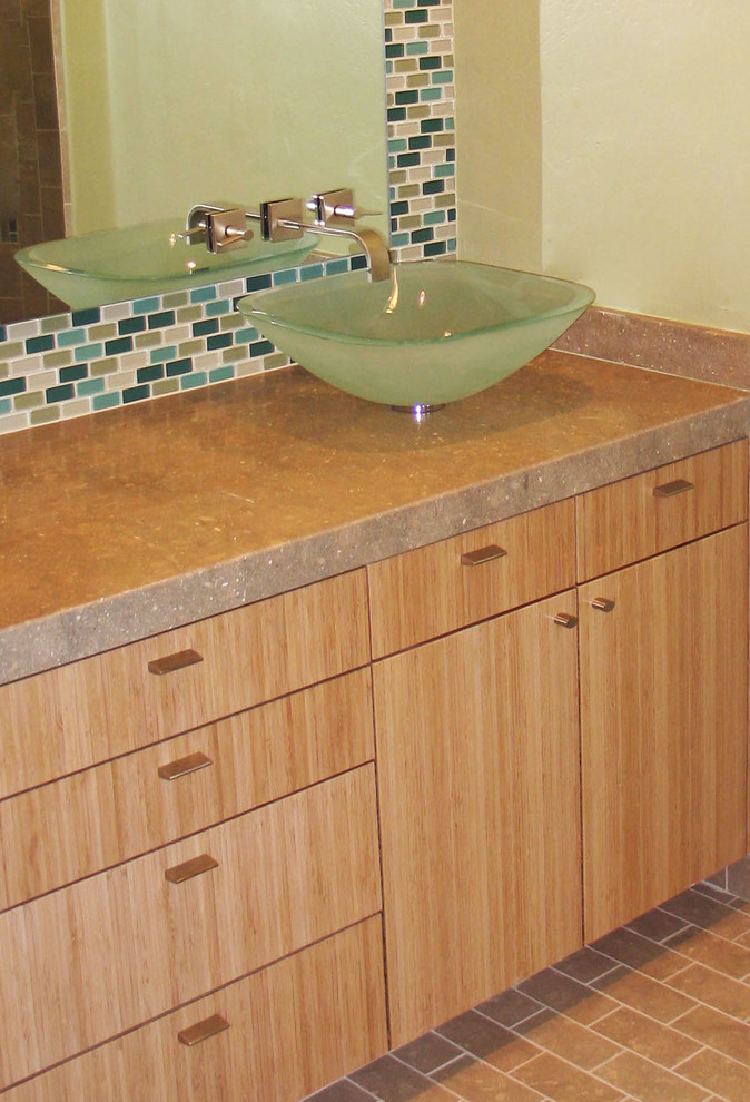 Modern inredning av ett mellanstort en-suite badrum, med ett fristående handfat, släta luckor, skåp i ljust trä, bänkskiva i kalksten, beige kakel, glasskiva och kalkstensgolv