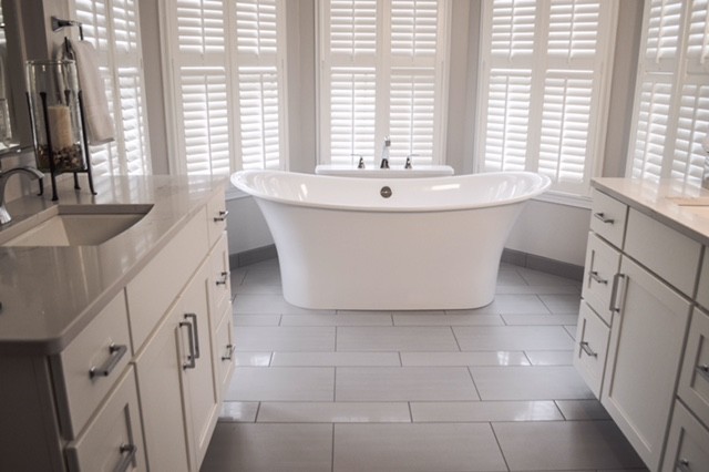 This is an example of a medium sized traditional ensuite bathroom in Cleveland with recessed-panel cabinets, white cabinets, a freestanding bath, an alcove shower, a two-piece toilet, grey tiles, porcelain tiles, grey walls, porcelain flooring, a submerged sink and engineered stone worktops.