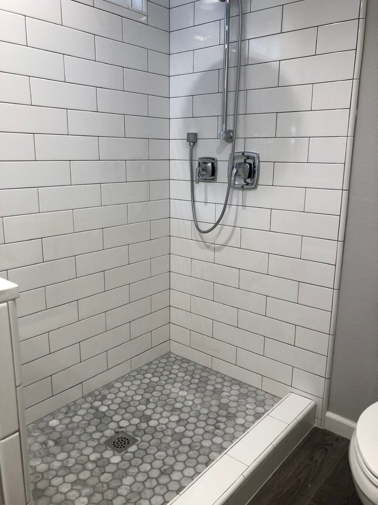 Photo of a medium sized traditional ensuite bathroom in Los Angeles with shaker cabinets, white cabinets, a walk-in shower, a two-piece toilet, white tiles, metro tiles, grey walls, vinyl flooring, engineered stone worktops, brown floors and white worktops.