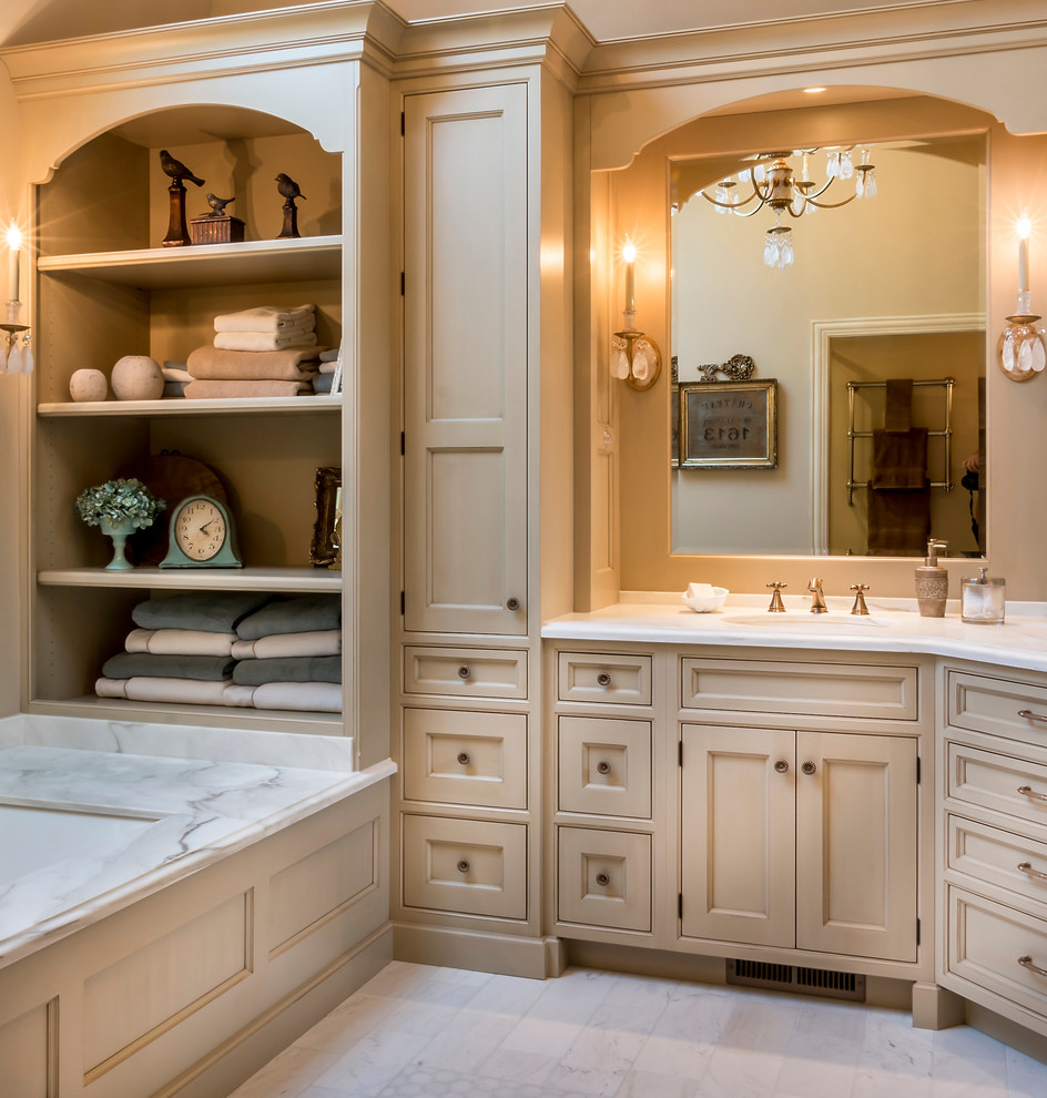 Corner shower - mid-sized traditional master marble floor corner shower idea in Chicago with an undermount sink, furniture-like cabinets, beige cabinets, marble countertops, an undermount tub and beige walls