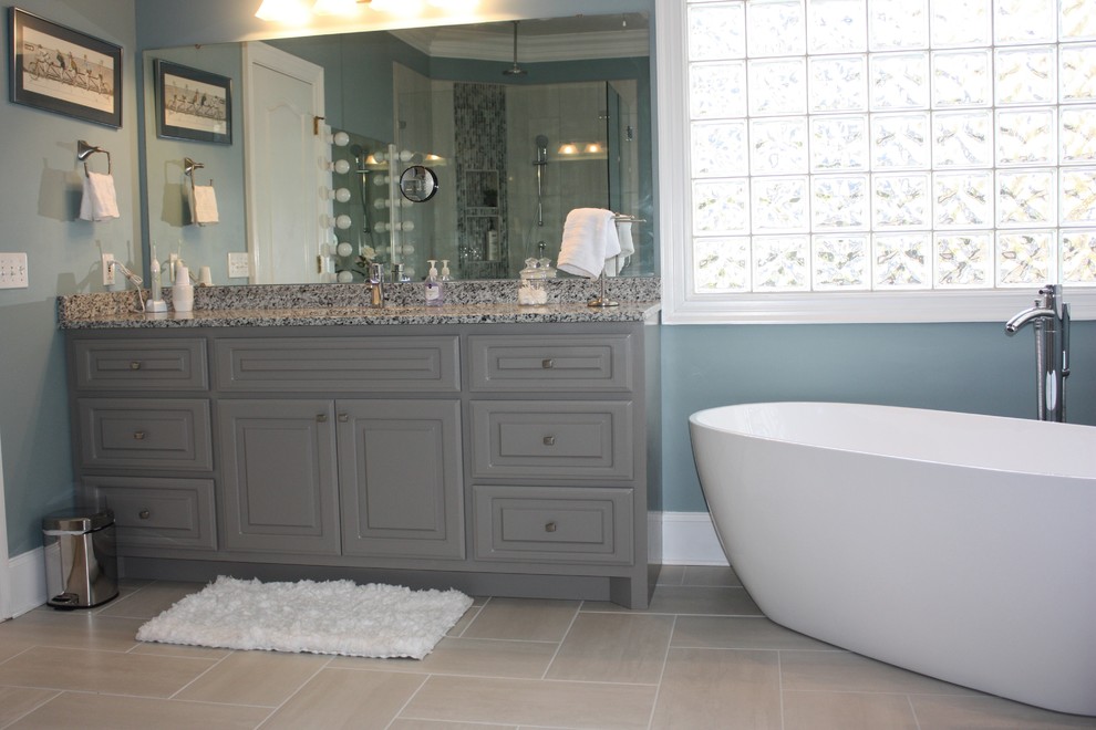 Пример оригинального дизайна: большая главная ванная комната в стиле неоклассика (современная классика) с фасадами с выступающей филенкой, серыми фасадами, отдельно стоящей ванной, синими стенами, врезной раковиной, столешницей из гранита, полом из керамогранита, угловым душем, серой плиткой, керамогранитной плиткой, серым полом и душем с распашными дверями