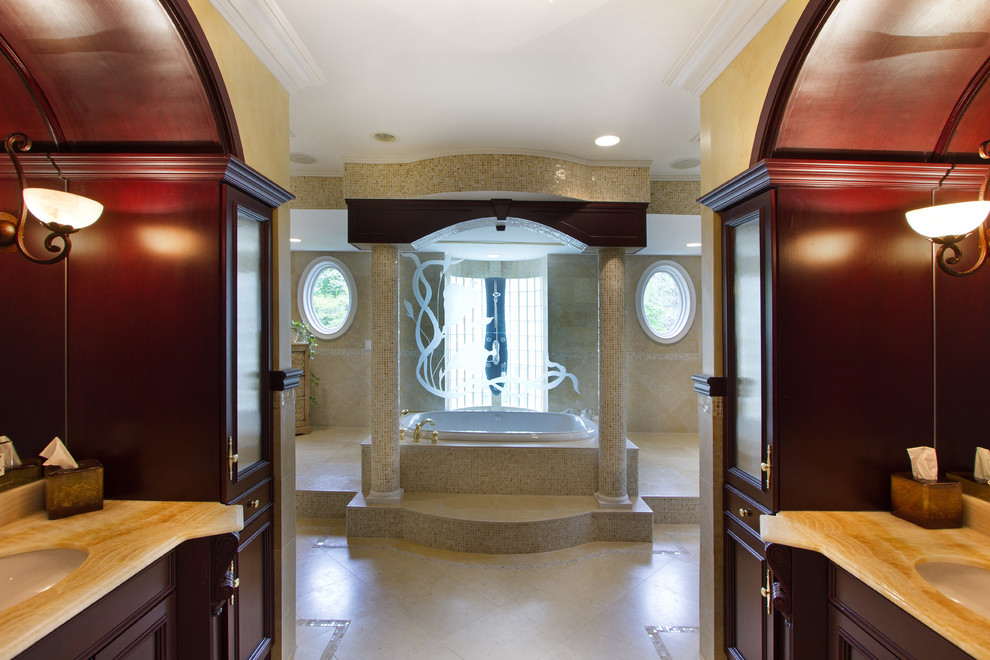 На фото: огромная главная ванная комната в стиле неоклассика (современная классика) с фасадами с выступающей филенкой, красными фасадами, накладной ванной, угловым душем, бежевой плиткой, плиткой мозаикой, бежевыми стенами, полом из травертина, врезной раковиной, мраморной столешницей, бежевым полом и коричневой столешницей