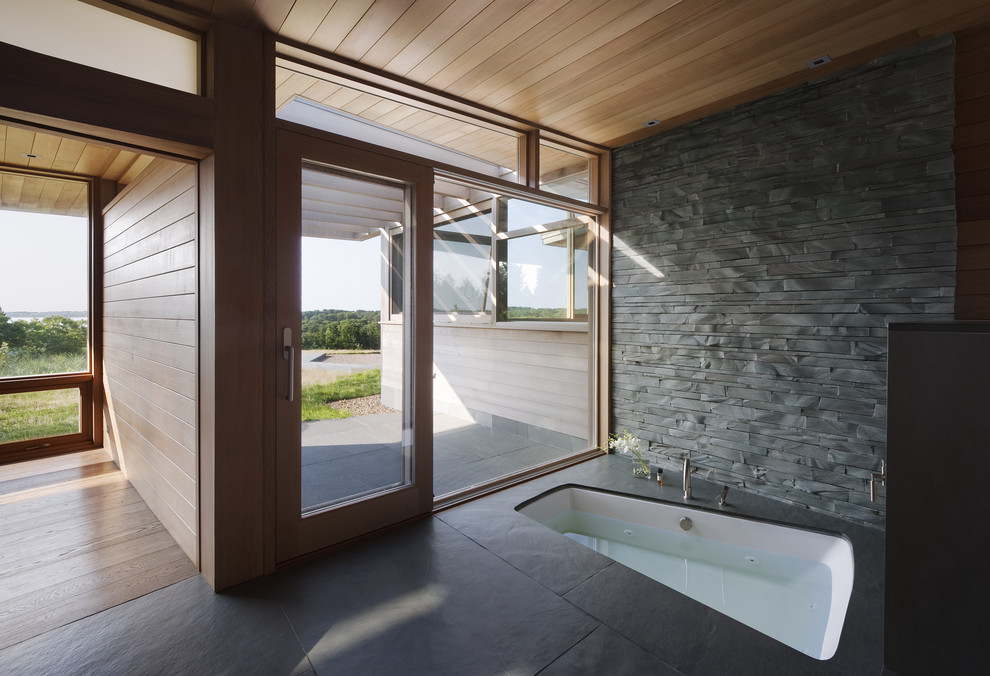 Idee per una stanza da bagno design con vasca sottopiano, piastrelle grigie e piastrelle in pietra