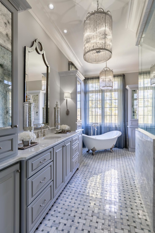 На фото: большая главная ванная комната в классическом стиле с серыми фасадами, отдельно стоящей ванной, душем в нише, раздельным унитазом, белой плиткой, керамической плиткой, серыми стенами, полом из керамической плитки, врезной раковиной, мраморной столешницей, серым полом, душем с распашными дверями, серой столешницей и фасадами с выступающей филенкой