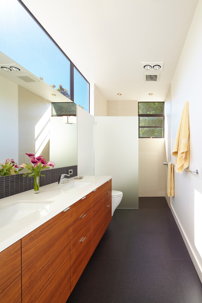 Trendy master black tile walk-in shower photo in San Francisco with an undermount sink, flat-panel cabinets, medium tone wood cabinets, quartz countertops, a one-piece toilet and white walls