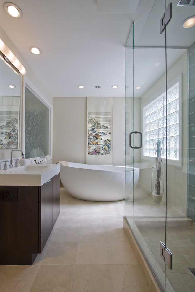 Inspiration for an expansive modern ensuite bathroom in Minneapolis with a freestanding bath, stone tiles, a submerged sink, solid surface worktops, an alcove shower, beige tiles, white walls, limestone flooring and dark wood cabinets.