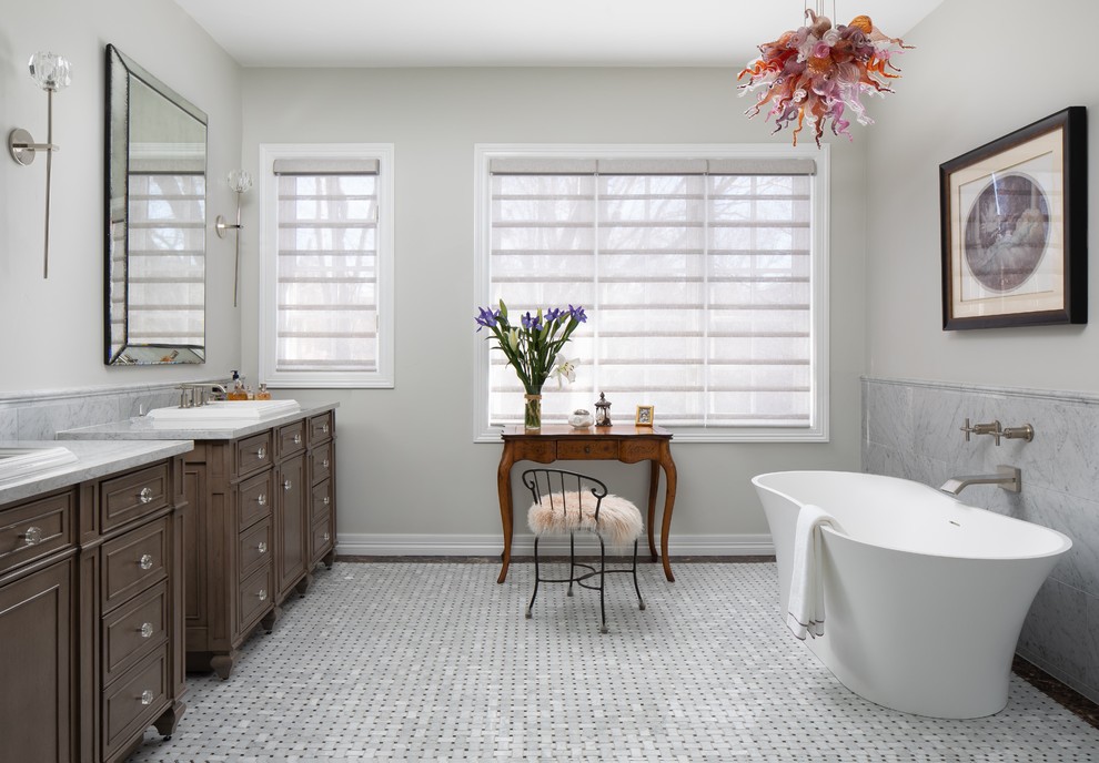 Идея дизайна: ванная комната в классическом стиле с фасадами с декоративным кантом, темными деревянными фасадами, отдельно стоящей ванной, серыми стенами, накладной раковиной, серым полом и белой столешницей