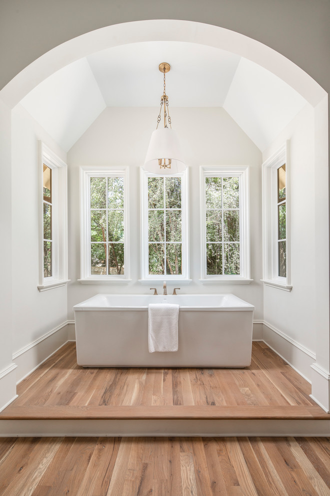 Immagine di una grande stanza da bagno padronale classica con vasca freestanding e pavimento in legno massello medio