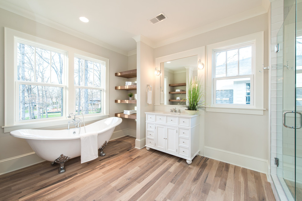 Inspiration pour une salle de bain principale craftsman de taille moyenne avec une baignoire sur pieds, un mur beige, parquet clair et un sol beige.