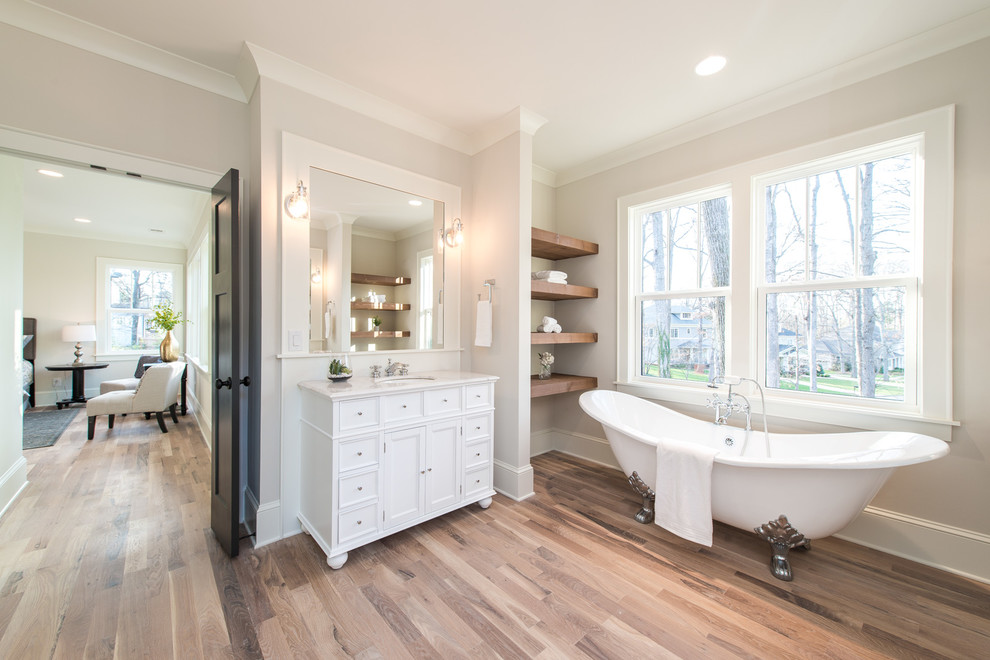 Medium sized classic ensuite bathroom in Charlotte with a claw-foot bath, beige walls, light hardwood flooring and beige floors.