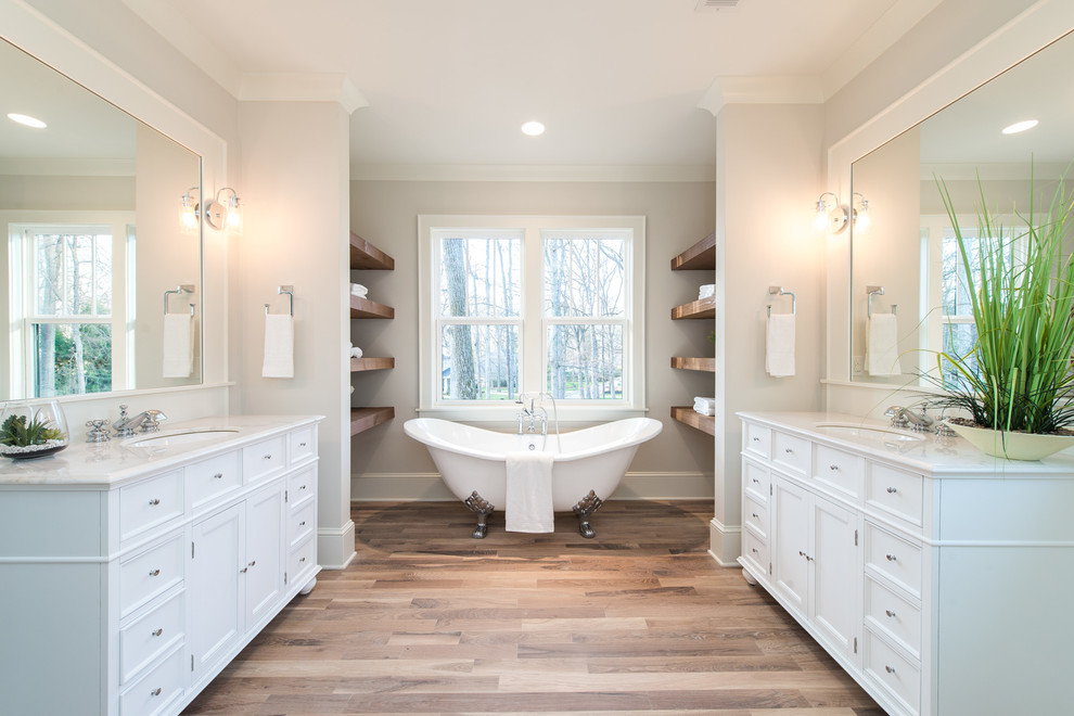 Exemple d'une salle de bain principale craftsman de taille moyenne avec une baignoire sur pieds, un mur beige, parquet clair et un sol beige.