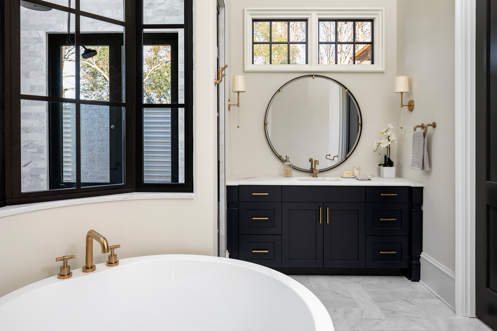 Klassisk inredning av ett stort en-suite badrum, med ett fristående badkar, en kantlös dusch, marmorgolv och dusch med gångjärnsdörr