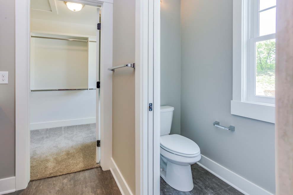 Example of a mid-sized arts and crafts master cement tile laminate floor bathroom design in Grand Rapids with shaker cabinets, gray cabinets, a two-piece toilet, an undermount sink, quartz countertops and a hinged shower door