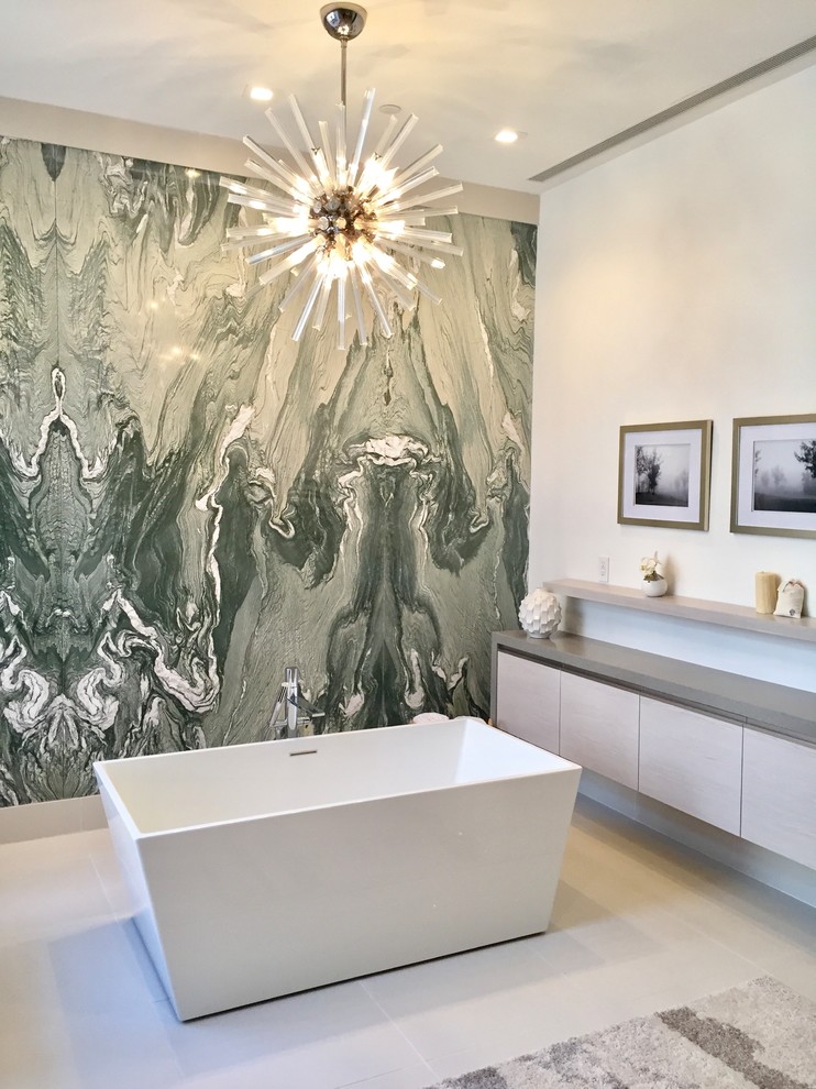 Contemporary bathroom in New York with flat-panel cabinets, grey cabinets, a freestanding bath, white tiles, white walls and white floors.