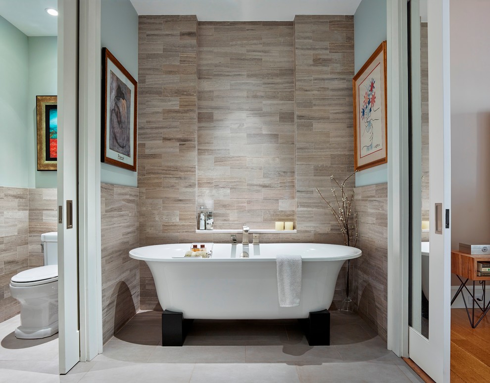 Imagen de cuarto de baño principal actual de tamaño medio con bañera exenta, baldosas y/o azulejos grises, baldosas y/o azulejos de piedra, paredes azules y suelo de baldosas de porcelana