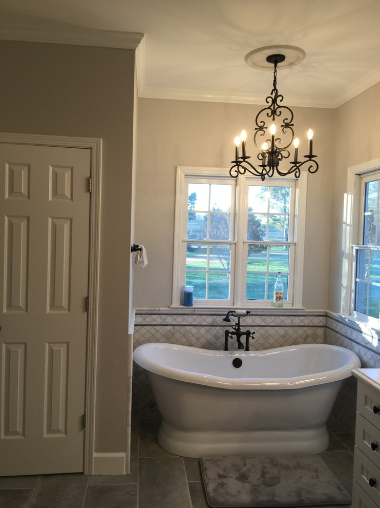 Design ideas for a country ensuite bathroom in Atlanta with white cabinets, a freestanding bath, white tiles, marble tiles, grey walls, ceramic flooring, engineered stone worktops and grey floors.
