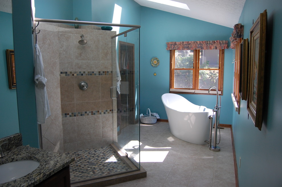 Exemple d'une grande salle de bain principale tendance en bois foncé avec un placard avec porte à panneau encastré, une baignoire indépendante, une douche d'angle, mosaïque, un mur bleu, un sol en carrelage de porcelaine, un lavabo encastré et un plan de toilette en stratifié.