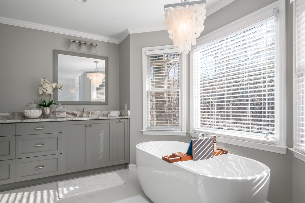 Foto på ett vintage grå badrum, med skåp i shakerstil, grå skåp, ett fristående badkar, grå väggar och grått golv