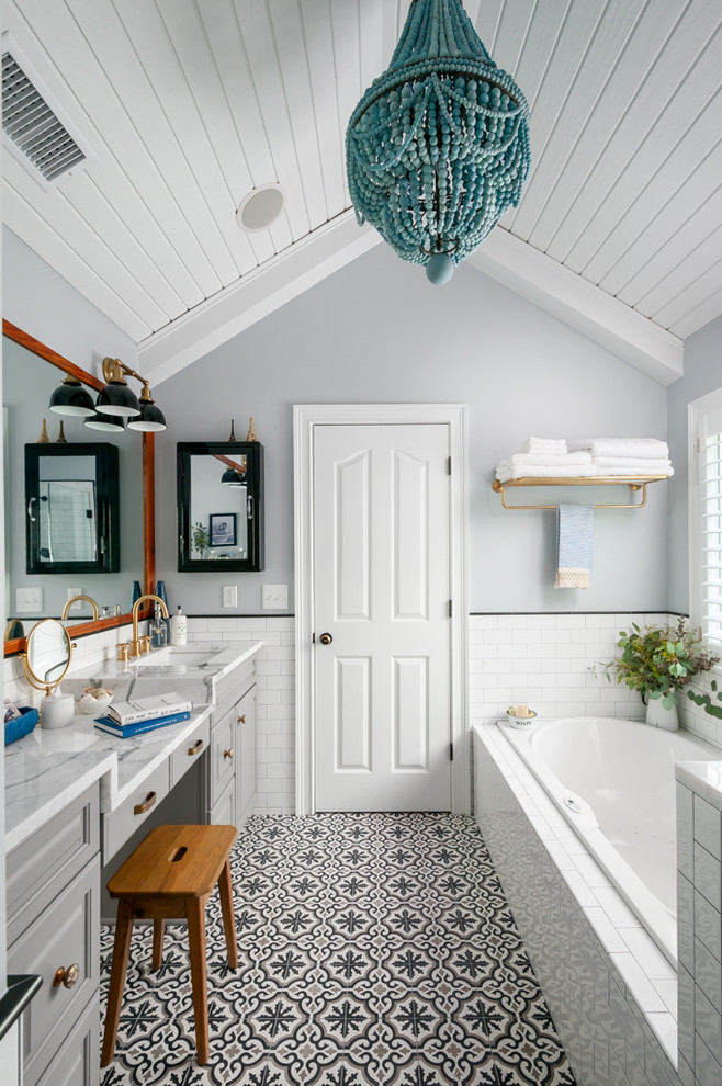 Cette photo montre une salle de bain chic avec un placard avec porte à panneau surélevé, des portes de placard grises, une baignoire posée, un carrelage blanc, un carrelage métro, un mur gris, carreaux de ciment au sol, un lavabo encastré et un sol multicolore.
