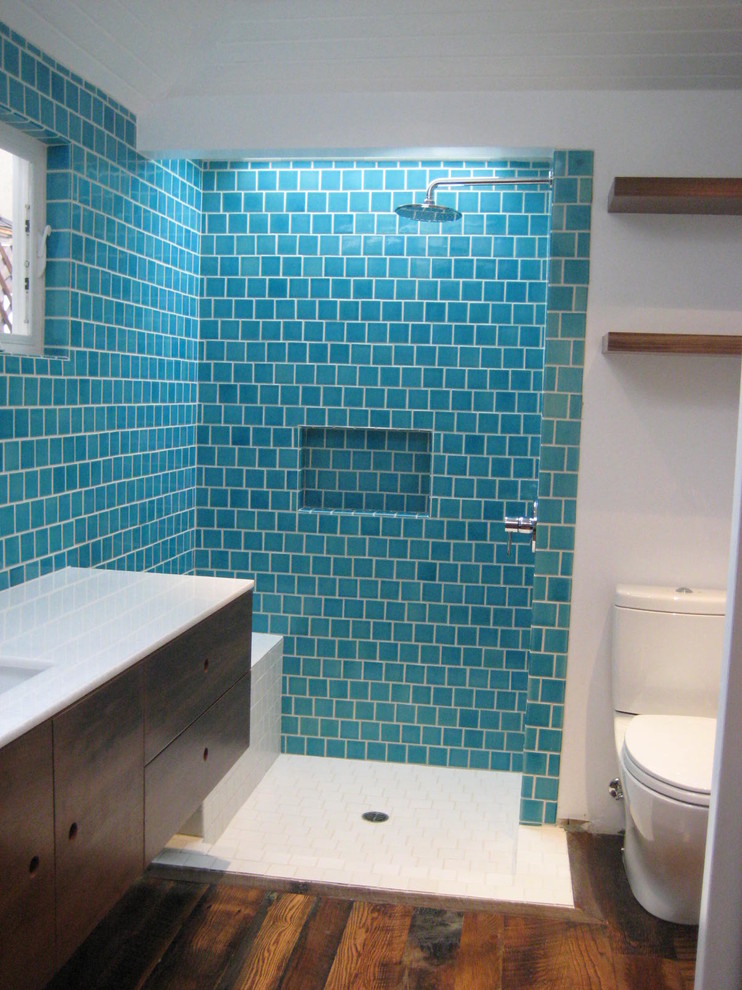 На фото: ванная комната среднего размера в стиле фьюжн с плоскими фасадами, темными деревянными фасадами, открытым душем, раздельным унитазом, синей плиткой, керамической плиткой, синими стенами, паркетным полом среднего тона, душевой кабиной, врезной раковиной и столешницей из искусственного камня с