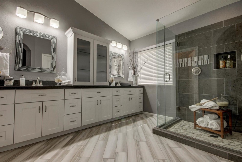 Example of a large trendy master black tile, gray tile, white tile and porcelain tile porcelain tile corner shower design in Phoenix with shaker cabinets, white cabinets, gray walls, an undermount sink and granite countertops