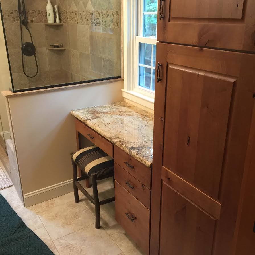 Cette image montre une douche en alcôve chalet en bois brun avec un placard avec porte à panneau surélevé, un carrelage beige et un plan de toilette en granite.