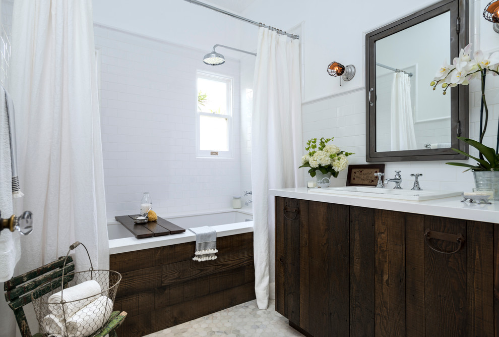 Cette image montre une petite salle de bain principale traditionnelle en bois vieilli avec un lavabo posé, un placard à porte plane, un plan de toilette en surface solide, une baignoire encastrée, un combiné douche/baignoire, WC séparés, un carrelage blanc, un carrelage métro, un mur blanc et un sol en marbre.