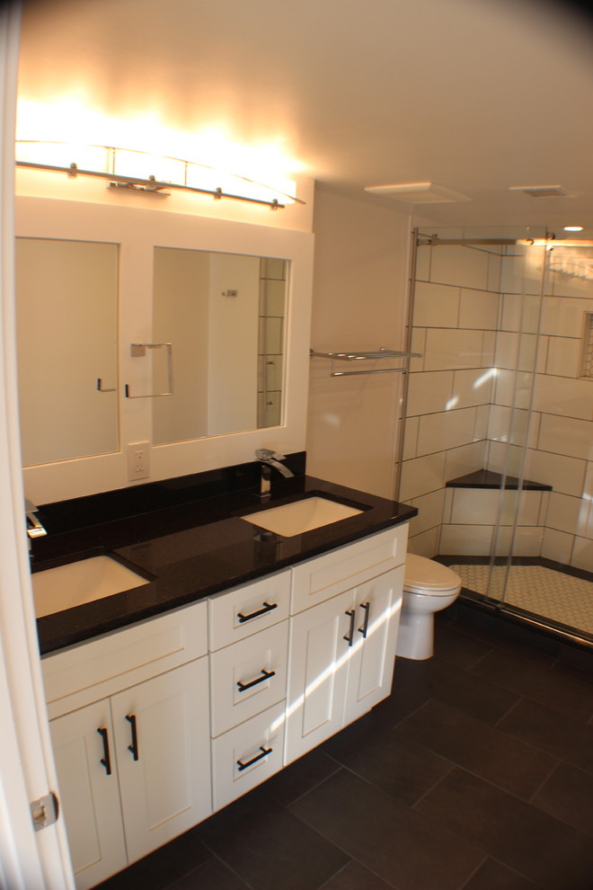 Свежая идея для дизайна: большая главная ванная комната в стиле модернизм с фасадами в стиле шейкер, белыми фасадами, душем в нише, унитазом-моноблоком, белой плиткой, керамогранитной плиткой, белыми стенами, полом из керамогранита, врезной раковиной, столешницей из гранита, черным полом и душем с раздвижными дверями - отличное фото интерьера