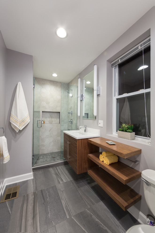 Photo of a medium sized contemporary ensuite bathroom in Chicago with flat-panel cabinets, medium wood cabinets, an alcove shower, a one-piece toilet, multi-coloured tiles, mosaic tiles, grey walls, marble flooring, a submerged sink and limestone worktops.