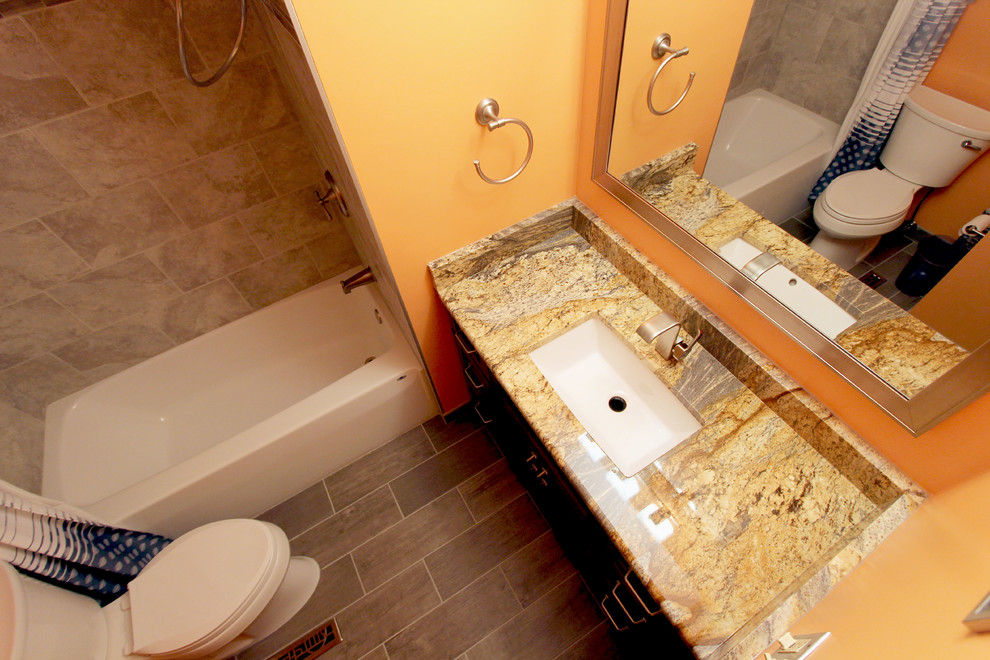 Cette image montre une petite salle de bain principale traditionnelle en bois foncé avec un lavabo encastré, un plan de toilette en granite, une baignoire en alcôve, un combiné douche/baignoire, WC séparés, un carrelage gris, des carreaux de porcelaine, un mur orange et un sol en carrelage de porcelaine.