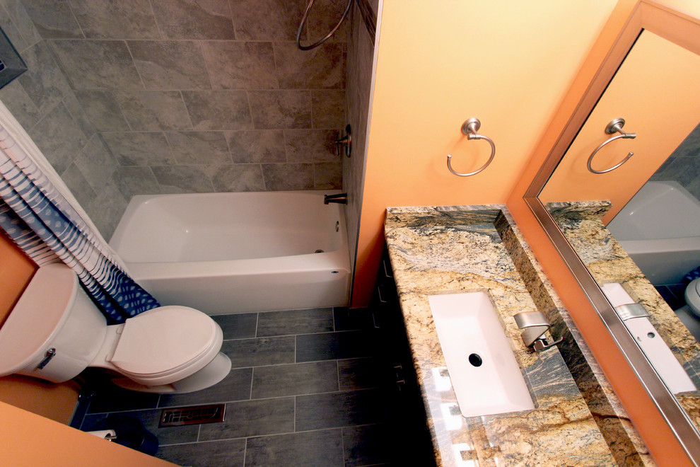 This is an example of a small traditional ensuite bathroom in Cleveland with a submerged sink, dark wood cabinets, granite worktops, an alcove bath, a shower/bath combination, a two-piece toilet, grey tiles, porcelain tiles, orange walls and porcelain flooring.
