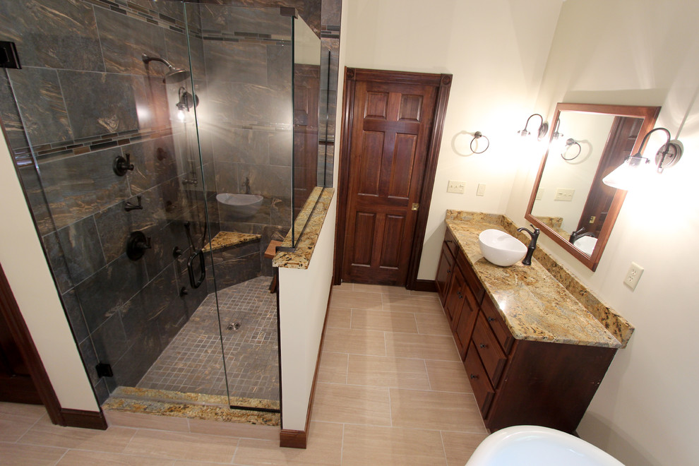 Inspiration for a large traditional bathroom in Cleveland with a vessel sink, raised-panel cabinets, dark wood cabinets, granite worktops, a corner shower, beige tiles, porcelain tiles, yellow walls and porcelain flooring.