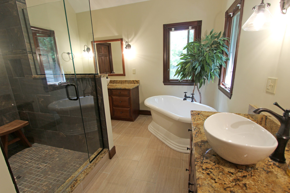 Exemple d'une grande salle de bain chic en bois foncé avec une vasque, un placard avec porte à panneau surélevé, un plan de toilette en granite, une douche d'angle, un carrelage beige, des carreaux de porcelaine, un mur jaune et un sol en carrelage de porcelaine.